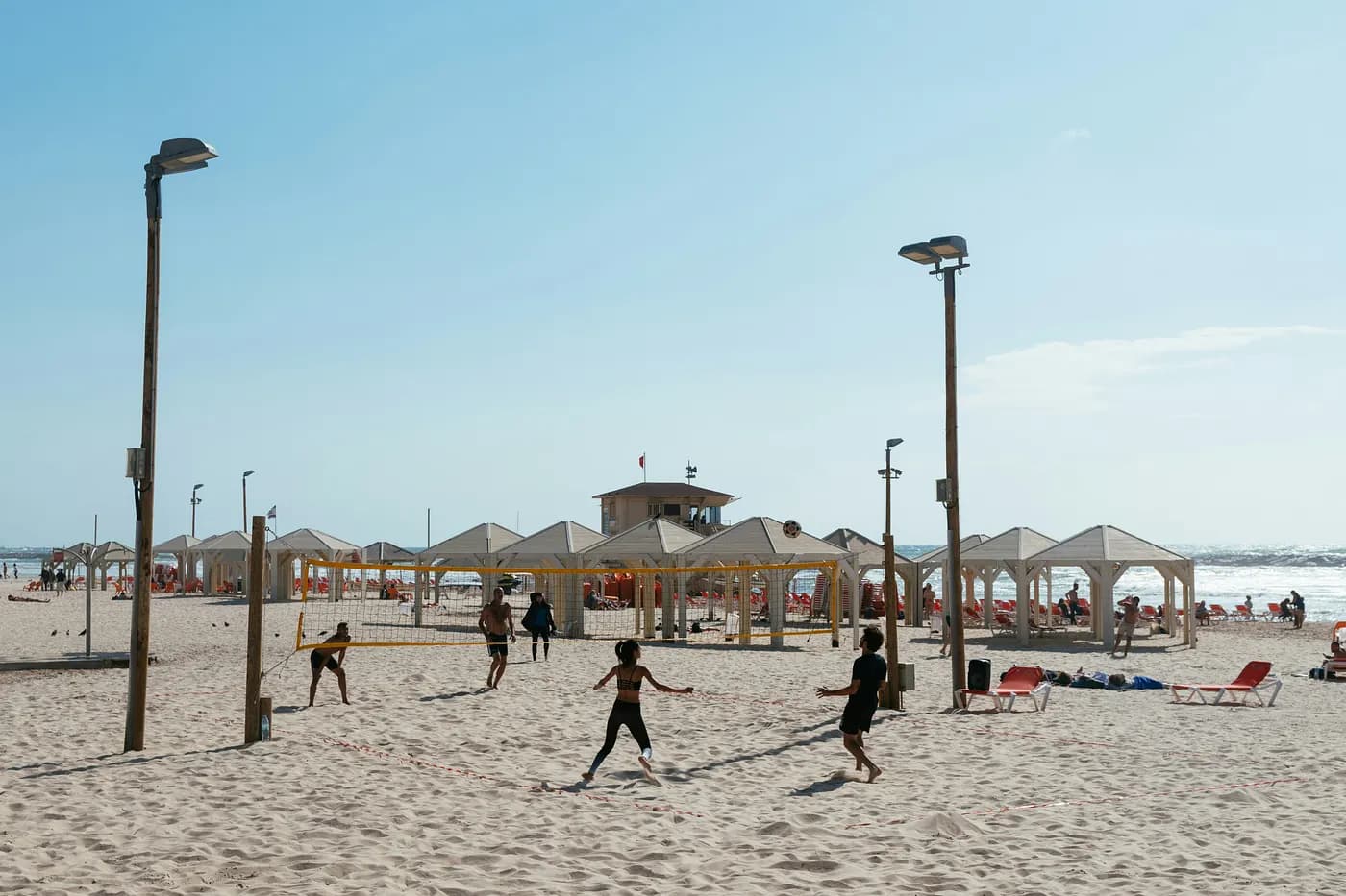 sunny beach with beachgoers playing volleyball