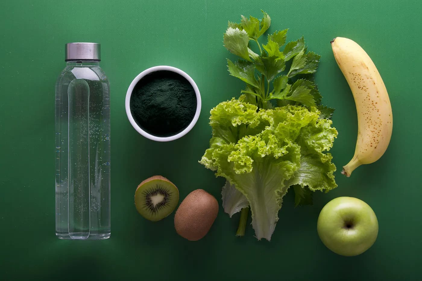 fruit, vegetables, and water on a green background